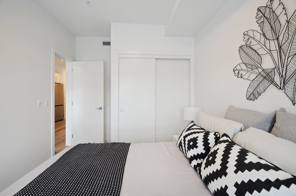 a bedroom with white walls and a bed with black and white pillows