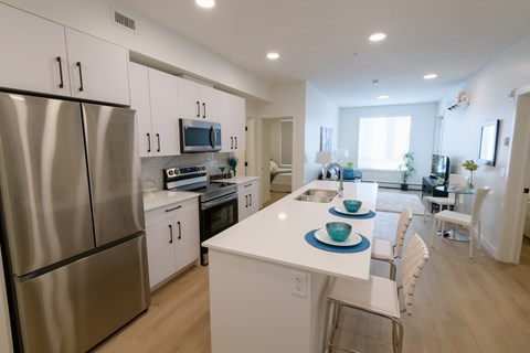 A modern kitchen with a stainless steel refrigerator and white cabinets.