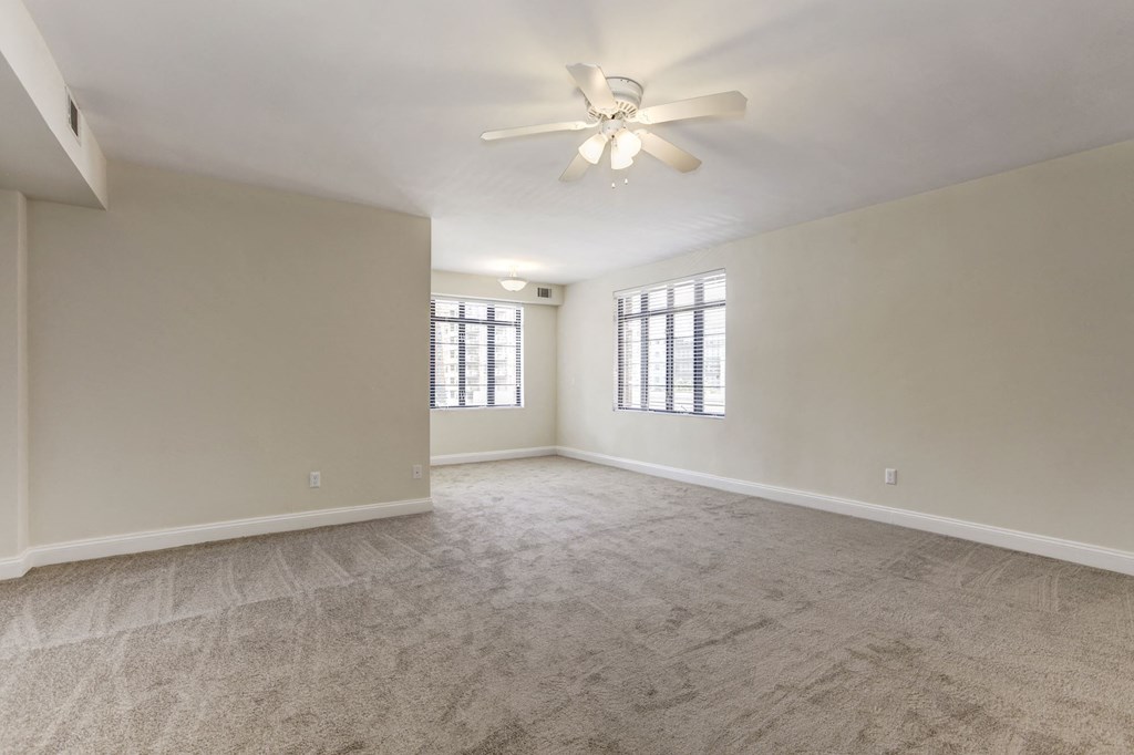A spacious room with a ceiling fan and carpeted floor.
