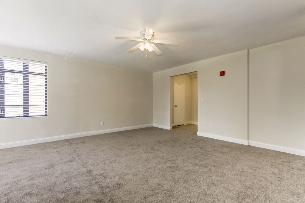 A room with a ceiling fan and carpeted floor.