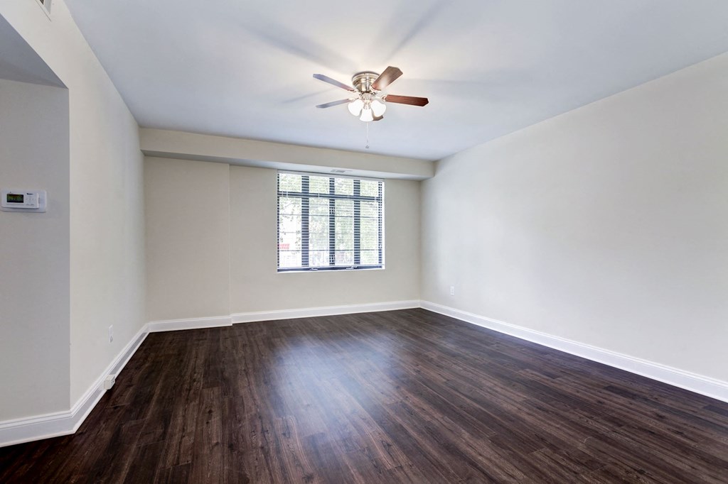 A room with a ceiling fan and a window with blinds.