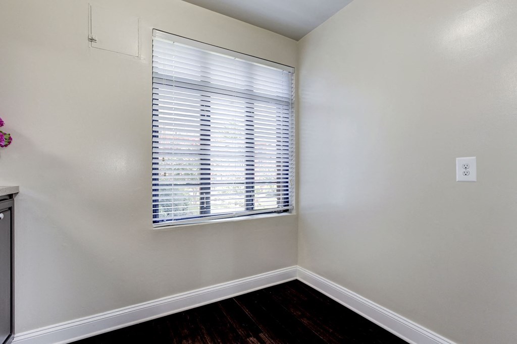 A room with a window covered by white blinds.