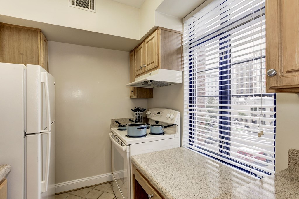 A kitchen with a white refrigerator, a white stove, and wooden cabinets.