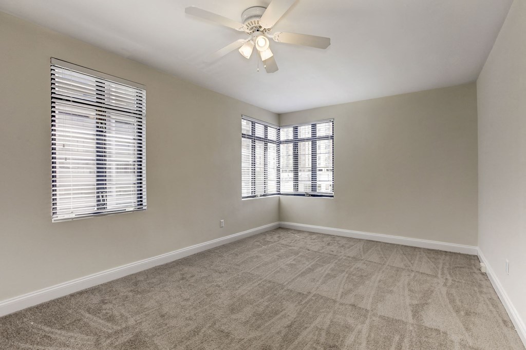 A room with a ceiling fan and a window with blinds.
