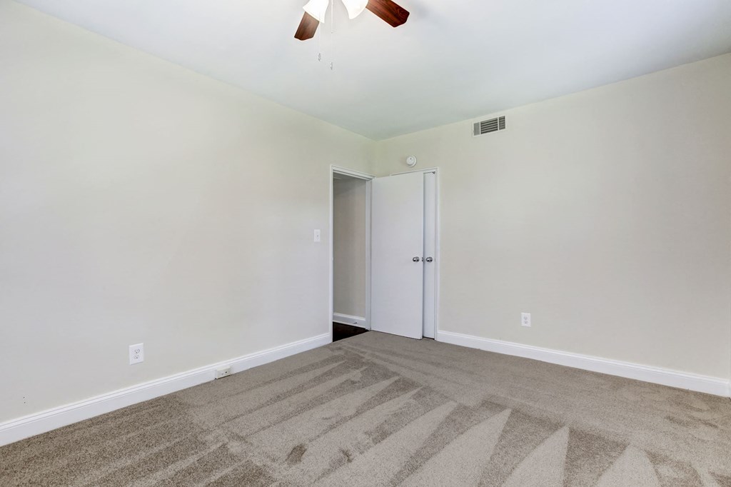A room with a carpeted floor and a ceiling fan.