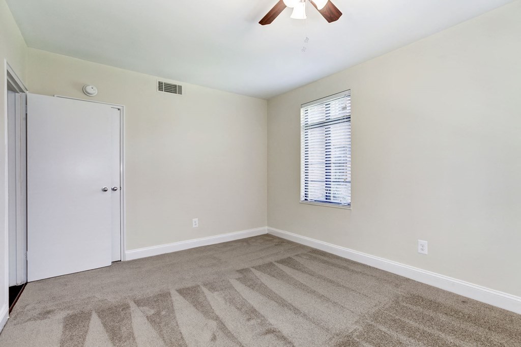A room with a carpeted floor and a ceiling fan.