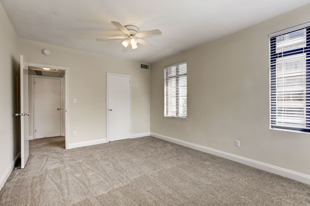 A room with a ceiling fan and carpeted floor.