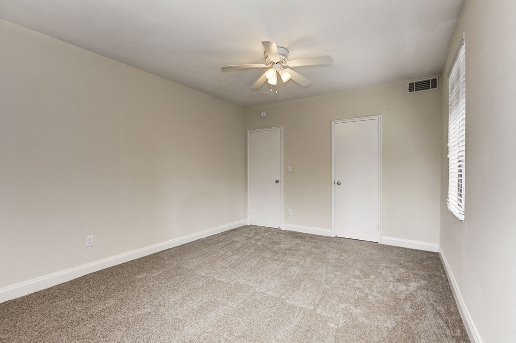 A room with a ceiling fan and carpeted floor.