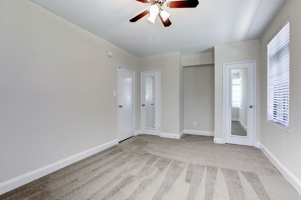 A room with a ceiling fan and carpeted floor.