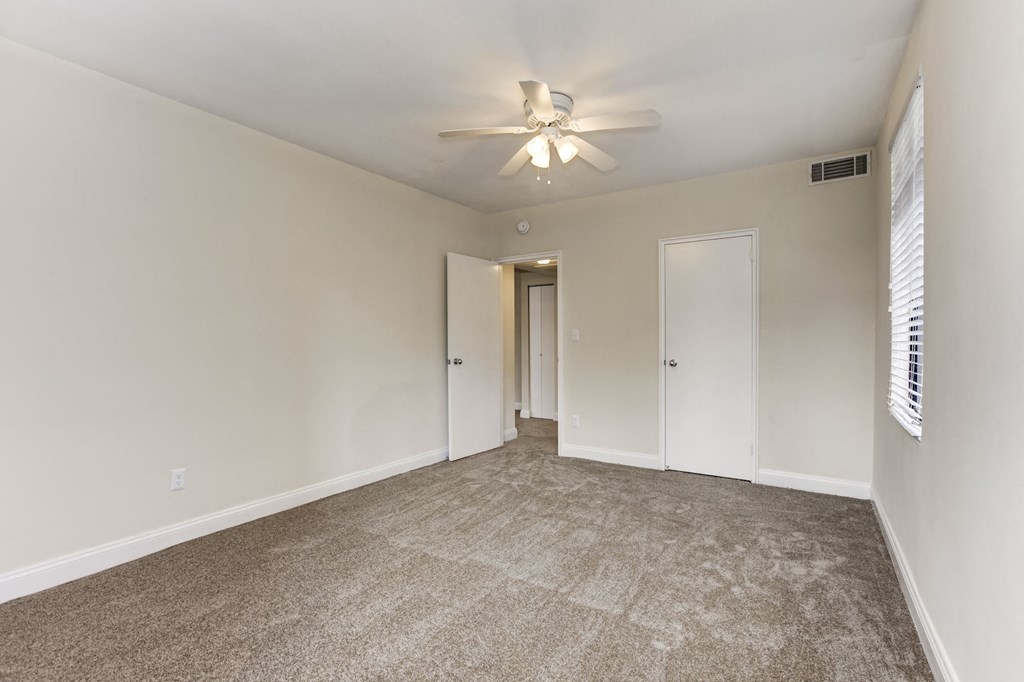 A room with a ceiling fan and carpeted floor.