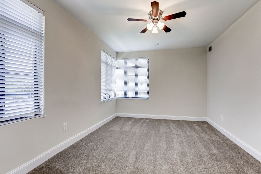 A room with a ceiling fan and carpeted floor.