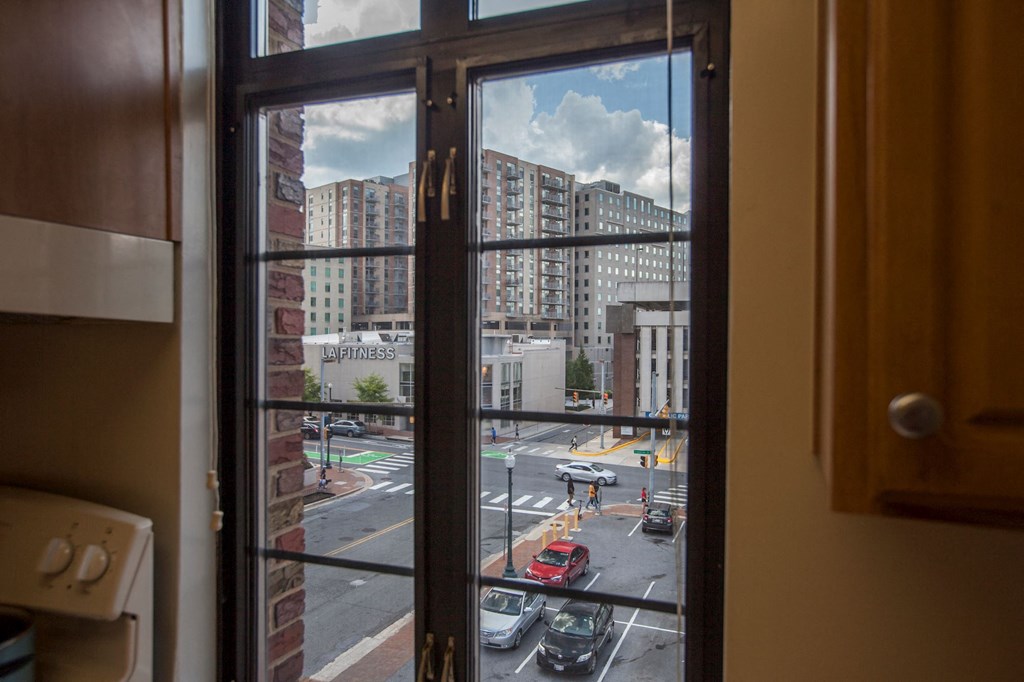 A view from a window looking out at a street with cars and buildings.