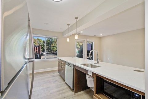 A modern kitchen with a refrigerator on the left and a microwave on the right.