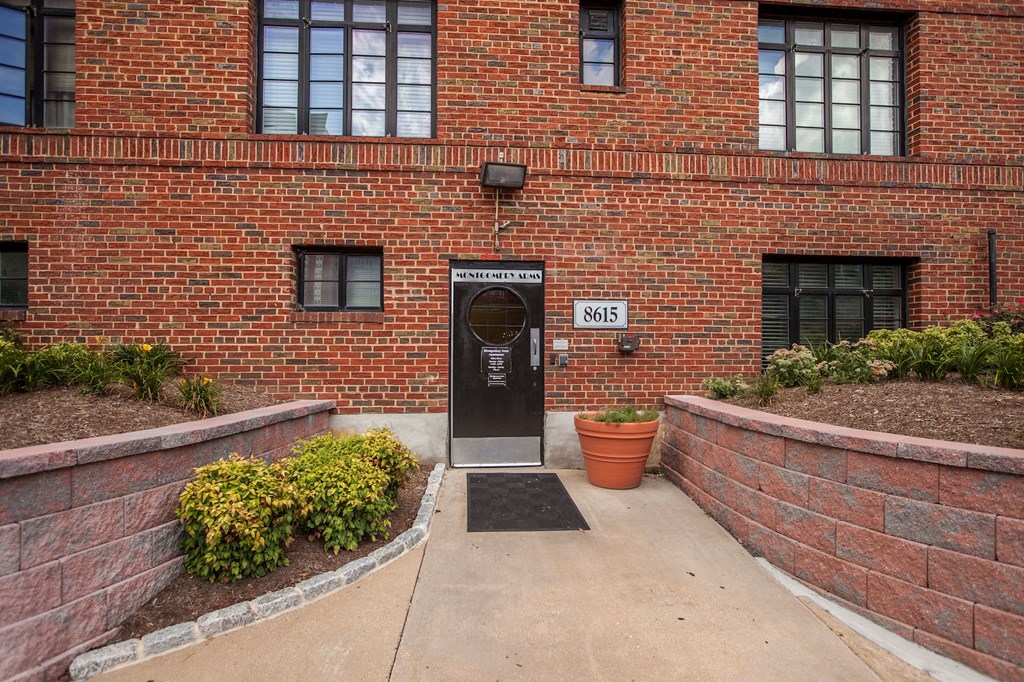 The image shows a brick building with a black door and a sign that reads "MATTHEWS LN 8615".