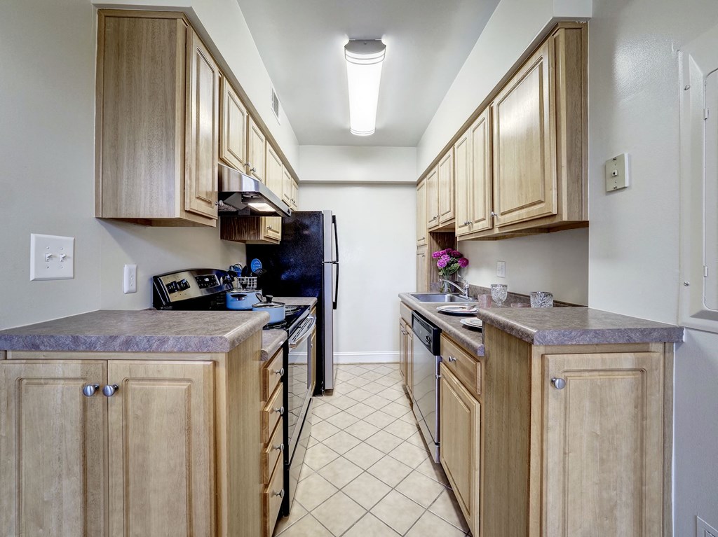 A kitchen with wooden cabinets and black appliances.