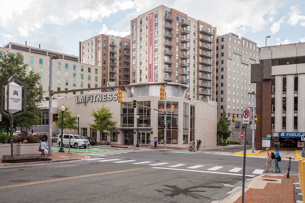 A street view of a city with a building that has a sign that says "Fitness".