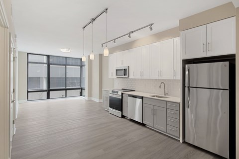 A modern kitchen with white cabinets and a wooden floor.