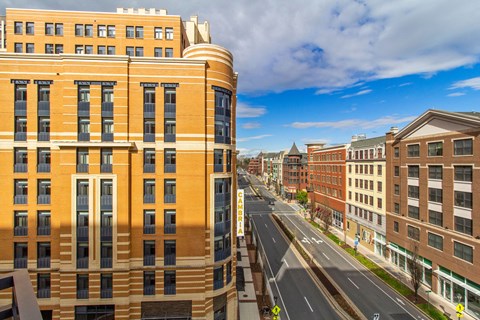 A large building with a curved corner is in the middle of a street.