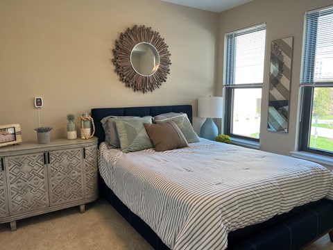 A bedroom with a bed, nightstand, and a mirror on the wall.