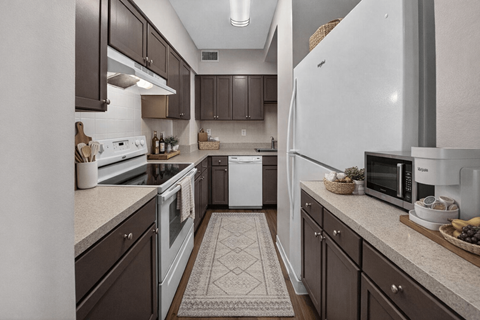 A kitchen with brown cabinets and a white refrigerator.