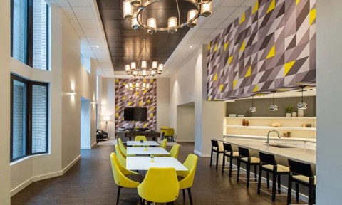 A modern dining room with a long table and yellow chairs.
