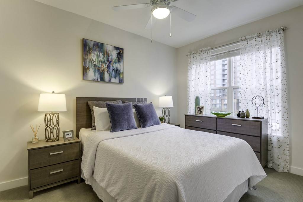 A bedroom with a large bed, two lamps, and a painting on the wall.