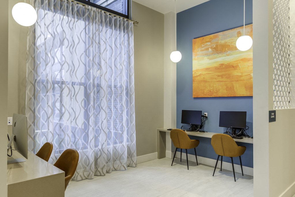 A room with a desk, chairs, and a painting on the wall.