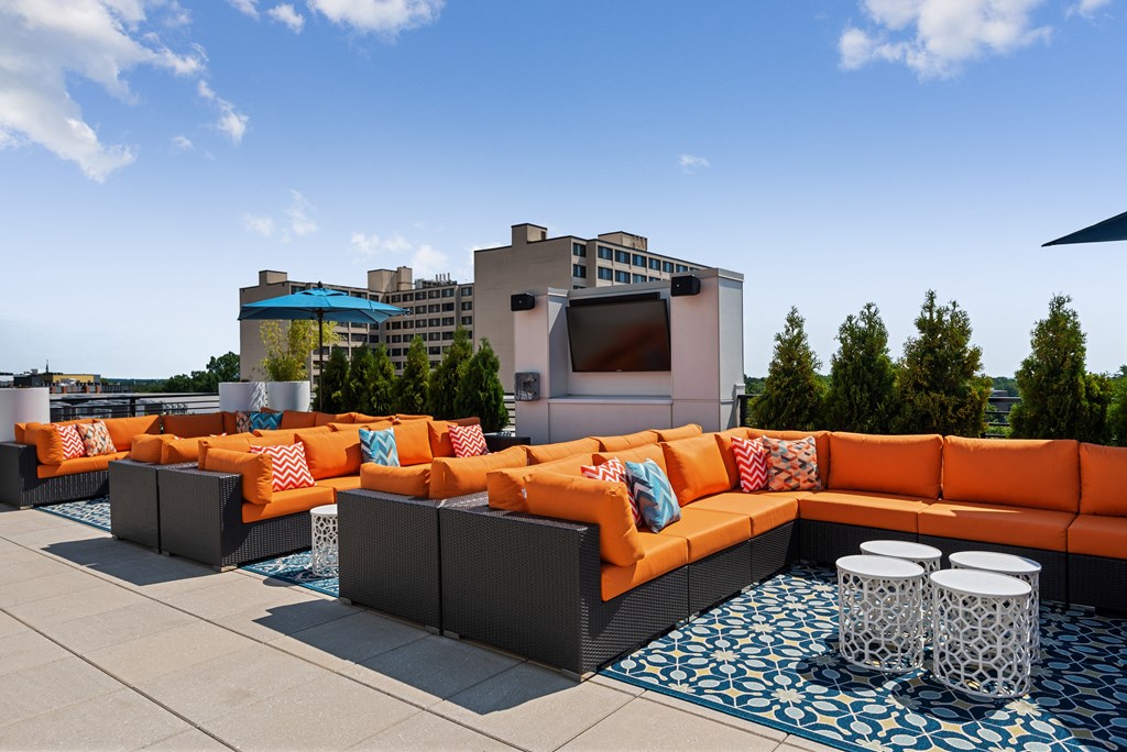 A patio with orange couches and a blue and white patterned rug.
