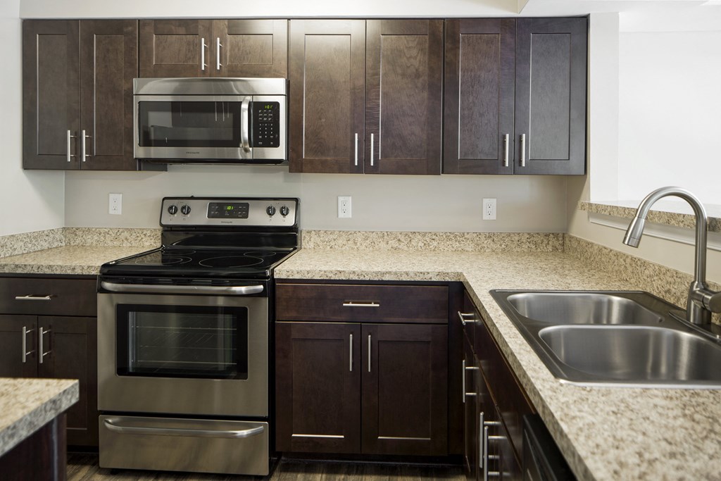 A kitchen with a stove, oven, microwave, and sink.