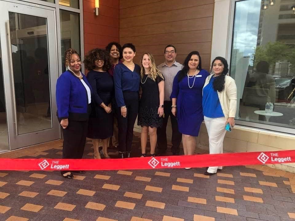 a group of people standing behind a red ribbon