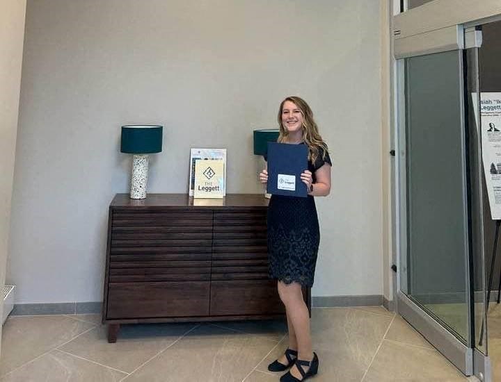 a woman holding a folder standing next to a dresser