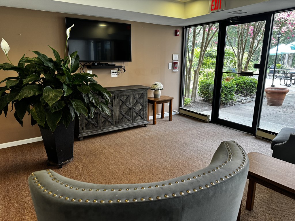 A grey armchair with studded trim sits in a room with a flat screen TV mounted on the wall.