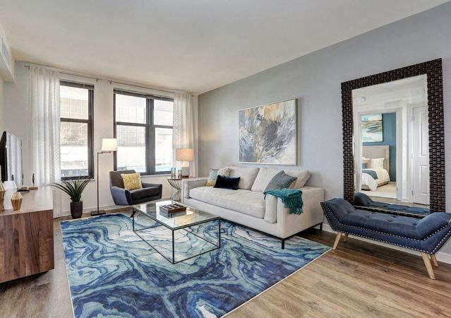 A living room with a white couch, a blue chair, and a large mirror.