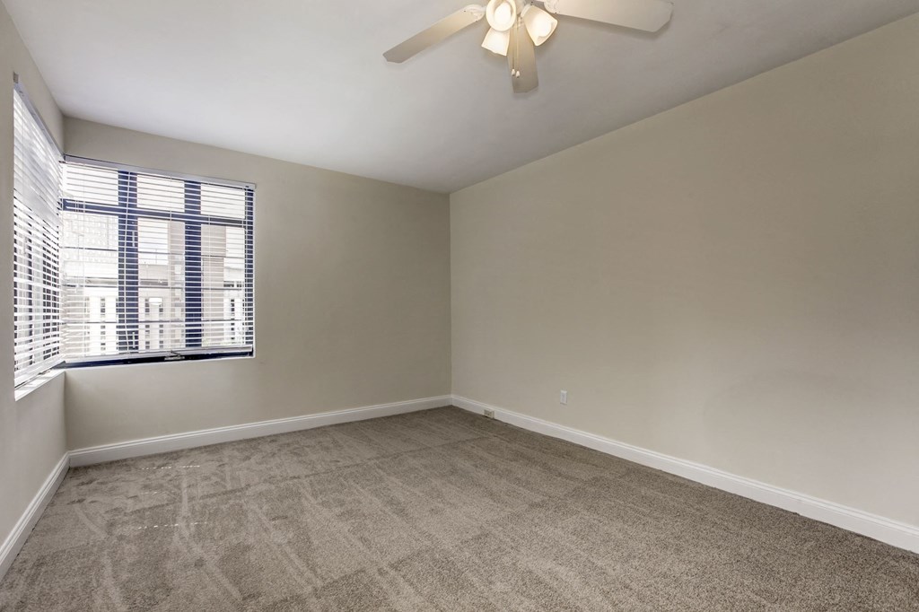 A room with a ceiling fan and carpeted floor.