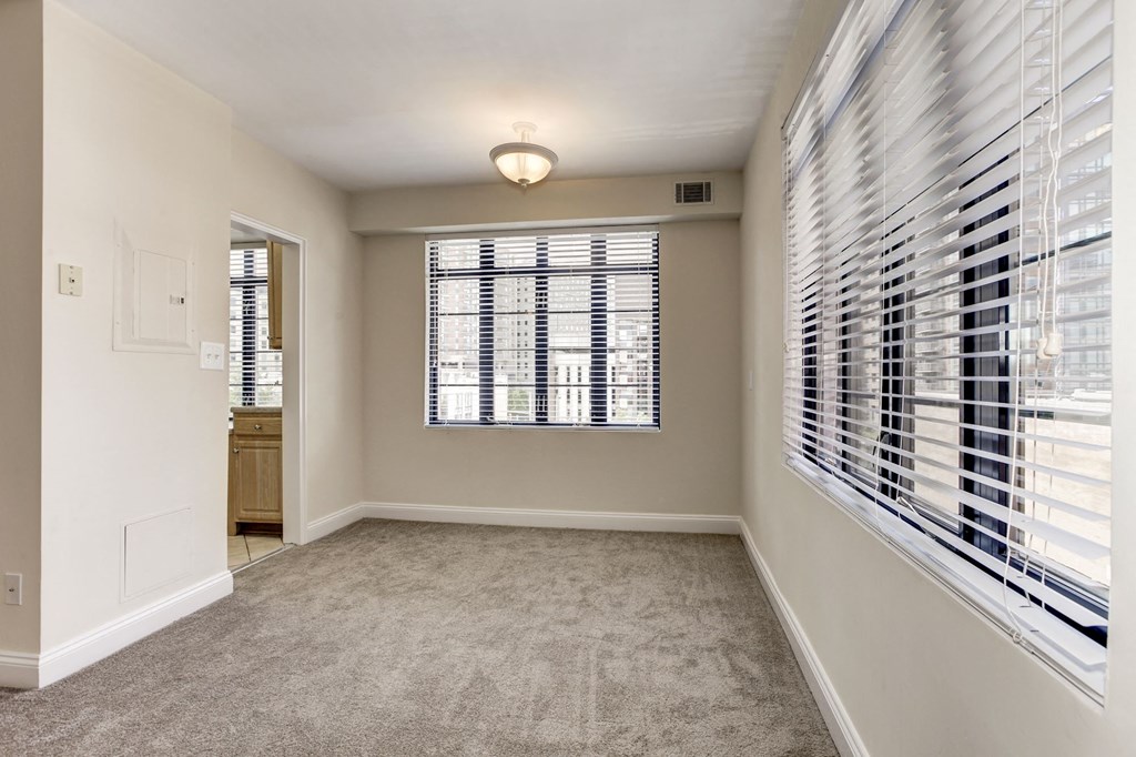A room with a window covered by white blinds.