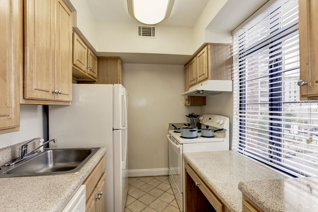 A kitchen with a refrigerator, sink, and stove.