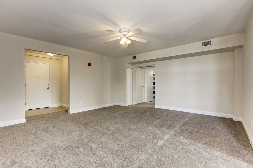 A spacious room with a ceiling fan and carpeted floor.