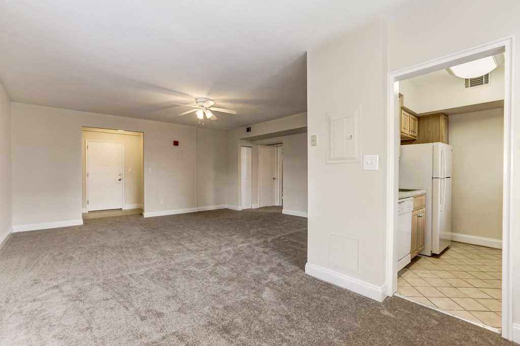 A spacious living room with a carpeted floor and a ceiling fan.