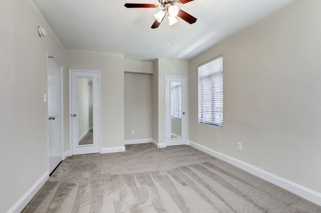 A room with a ceiling fan and carpeted floor.