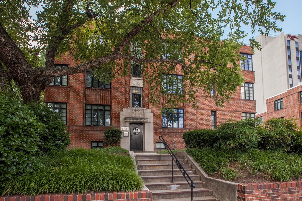A red brick building with a tree in front.