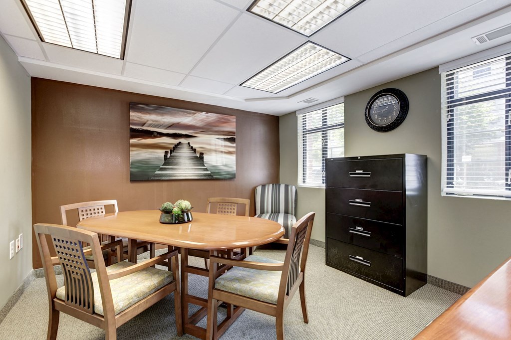 A conference room with a table, chairs, and a painting on the wall.