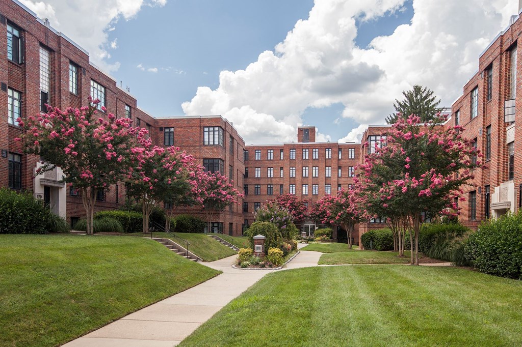 A tree with pink flowers is in front of a brick building.