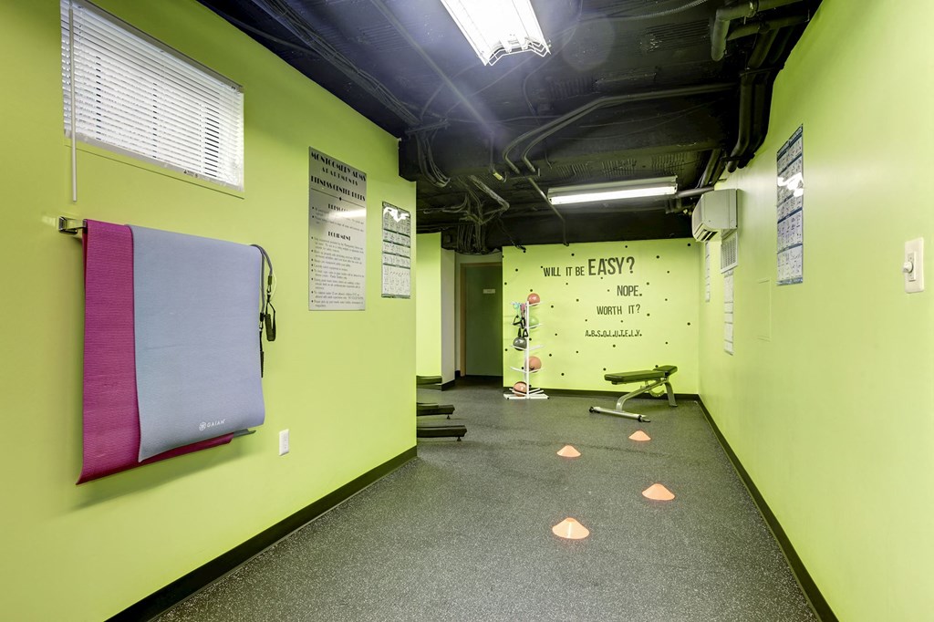A gym with a green wall and a sign that says "Will it be easy?".