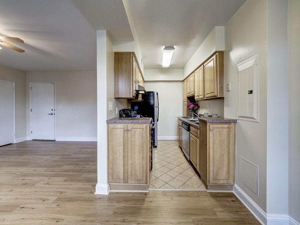 A kitchen with wooden cabinets and a black refrigerator.