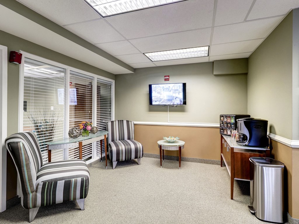 A waiting room with striped chairs and a television on the wall.