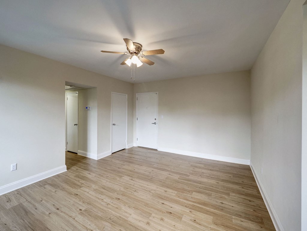 A room with a ceiling fan and wooden flooring.