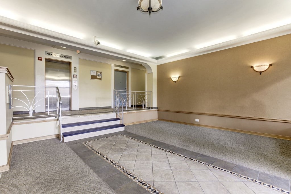 A spacious room with a carpeted floor and a staircase with a railing.