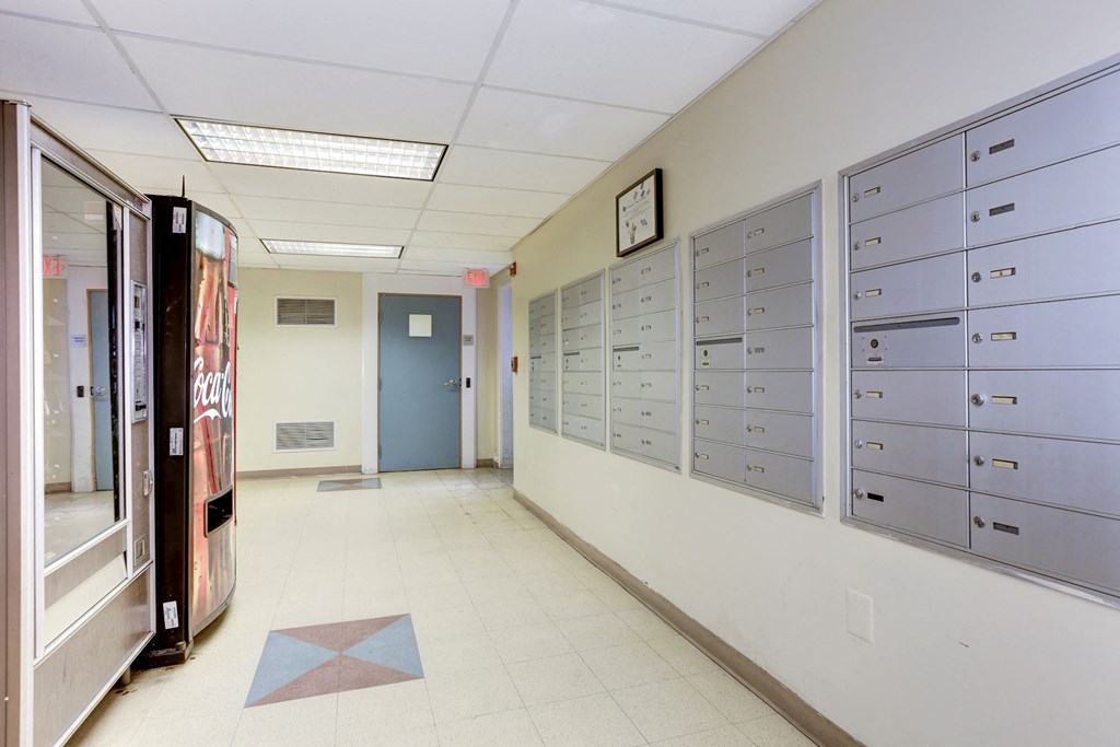 A hallway with a row of mailboxes on the wall.