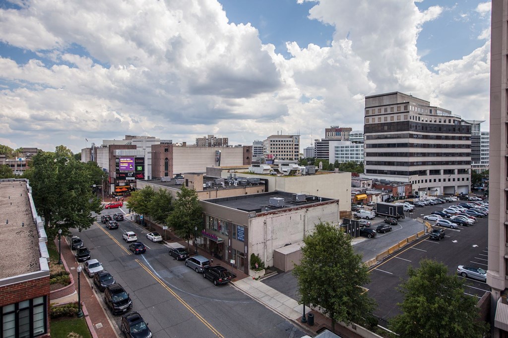 A city street with cars parked on the side and buildings in the background.