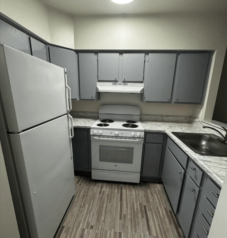 A kitchen with a white refrigerator, a white sink, a white stove, and a white countertop.